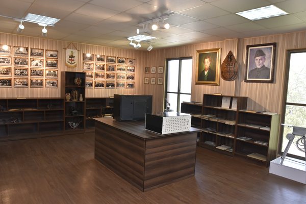 A wall of framed team photographs and house shields, with portraits hung beside the window